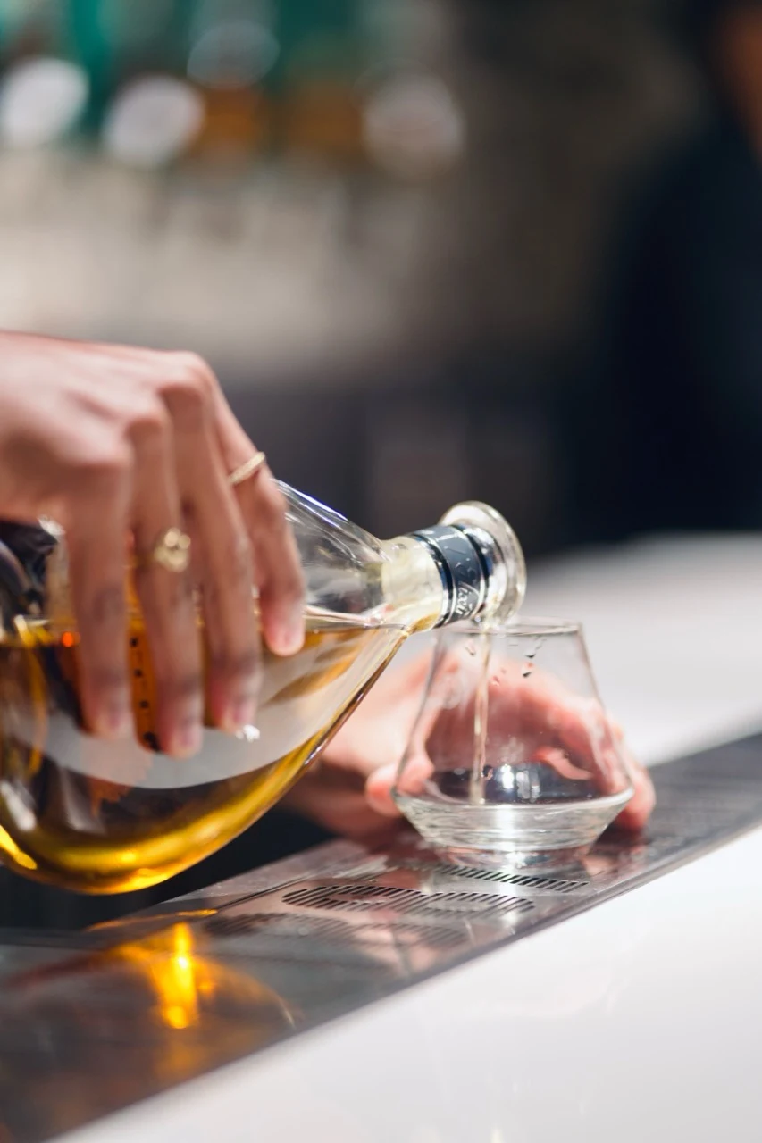 Main servant un spiritueux ambré dans un verre