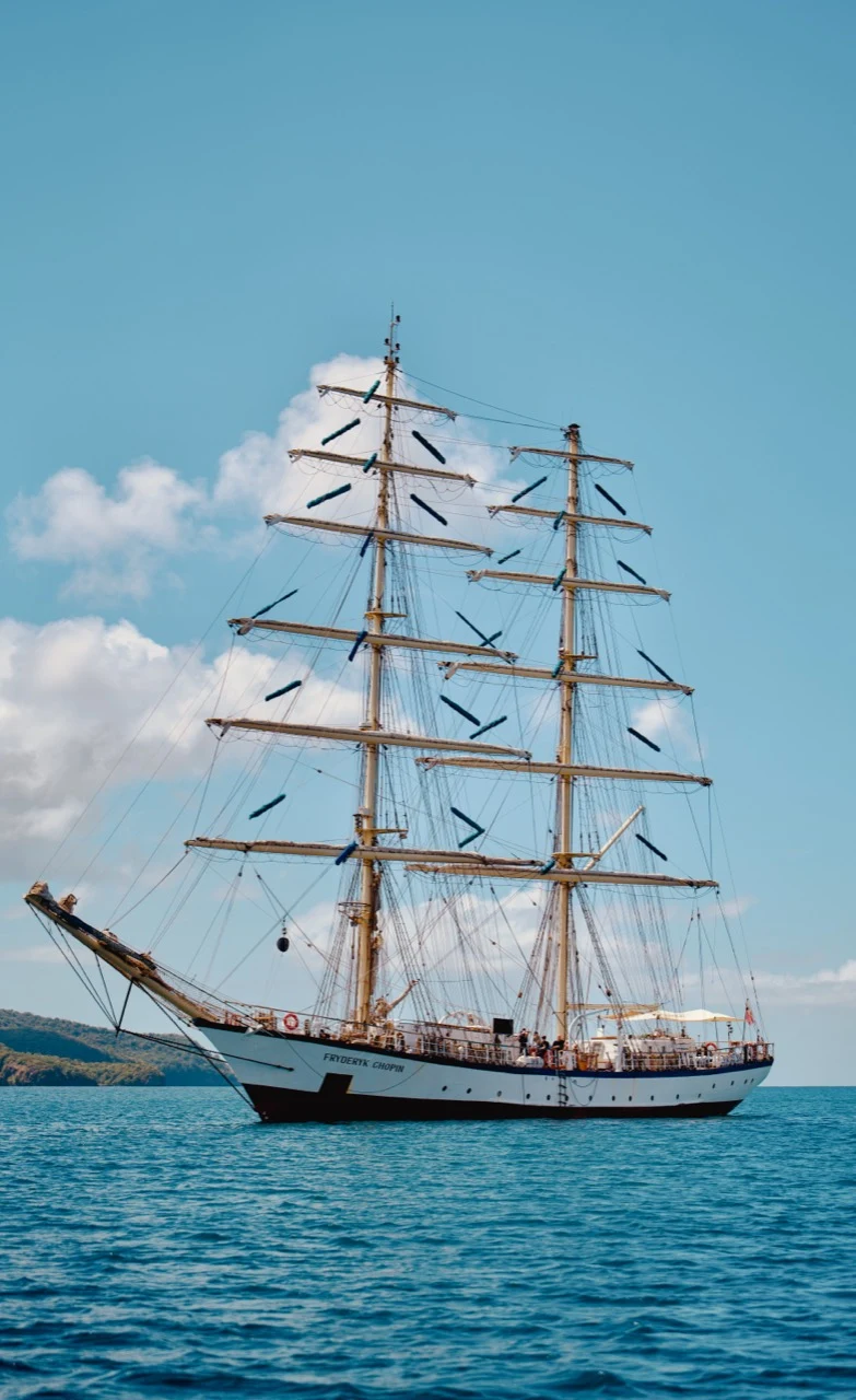 Grand voilier blanc Frédéric Chopin naviguant près de la côte