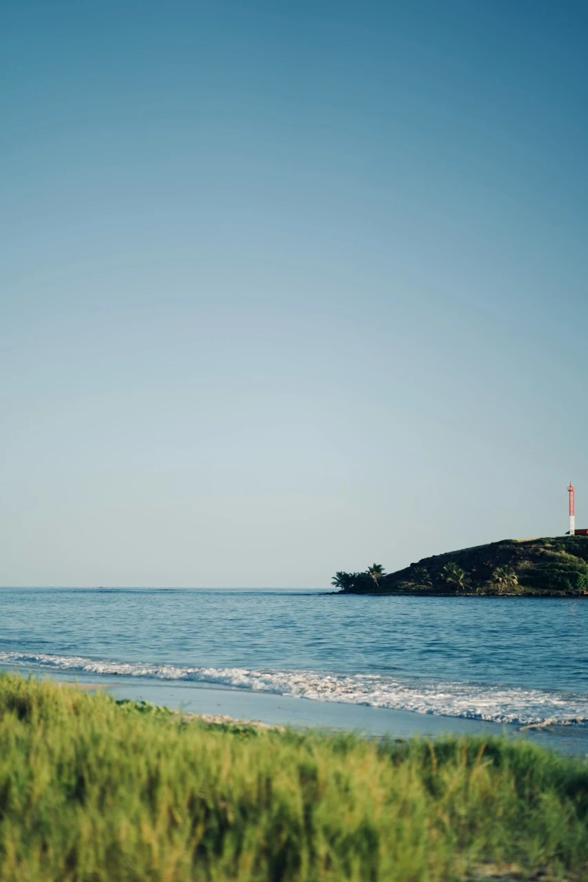 Petit phare rouge et blanc au bout d’une pointe tropicale