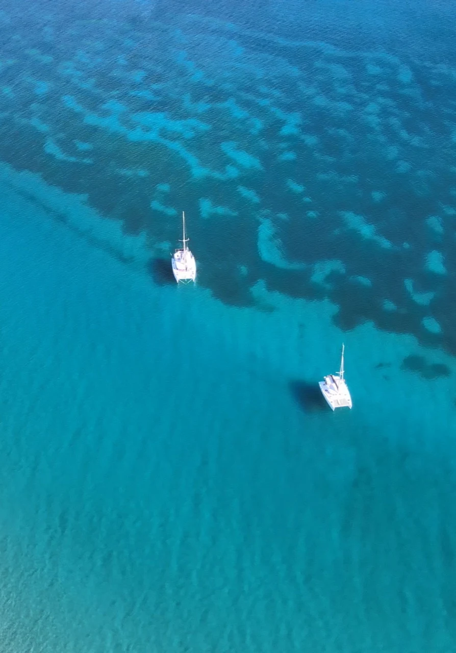Deux catamarans blancs vus du ciel dans une eau turquoise