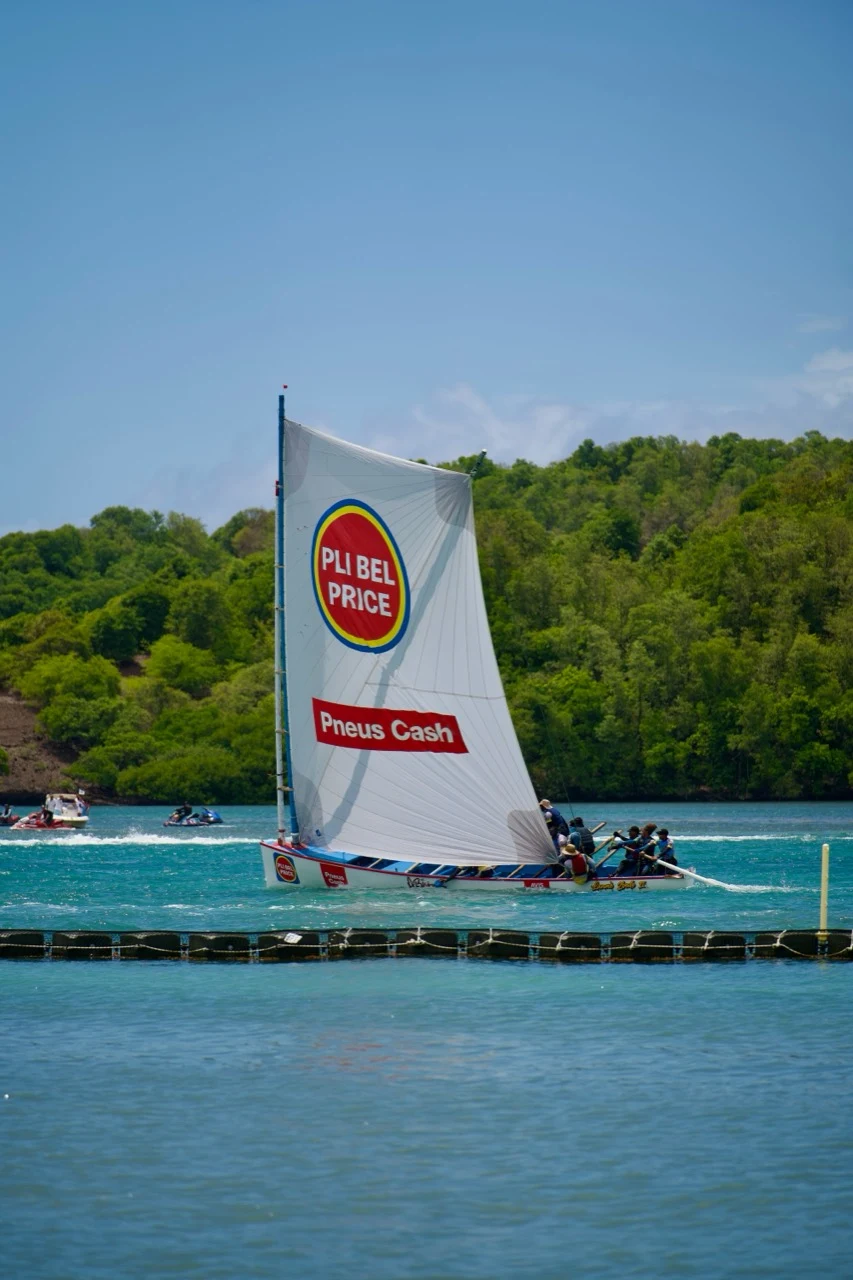 Yole martiniquaise en course devant une côte boisée