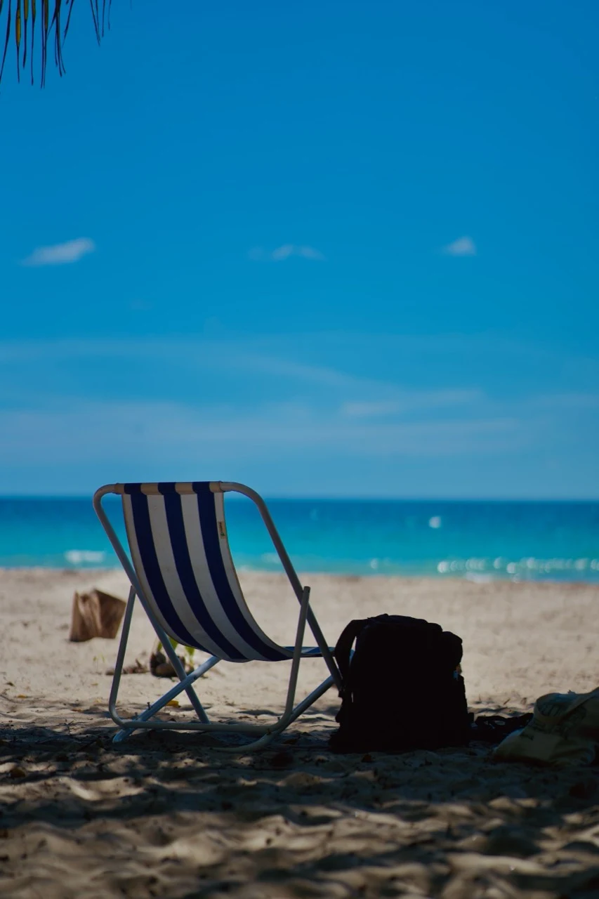 Chaise rayée vide face à une plage tropicale