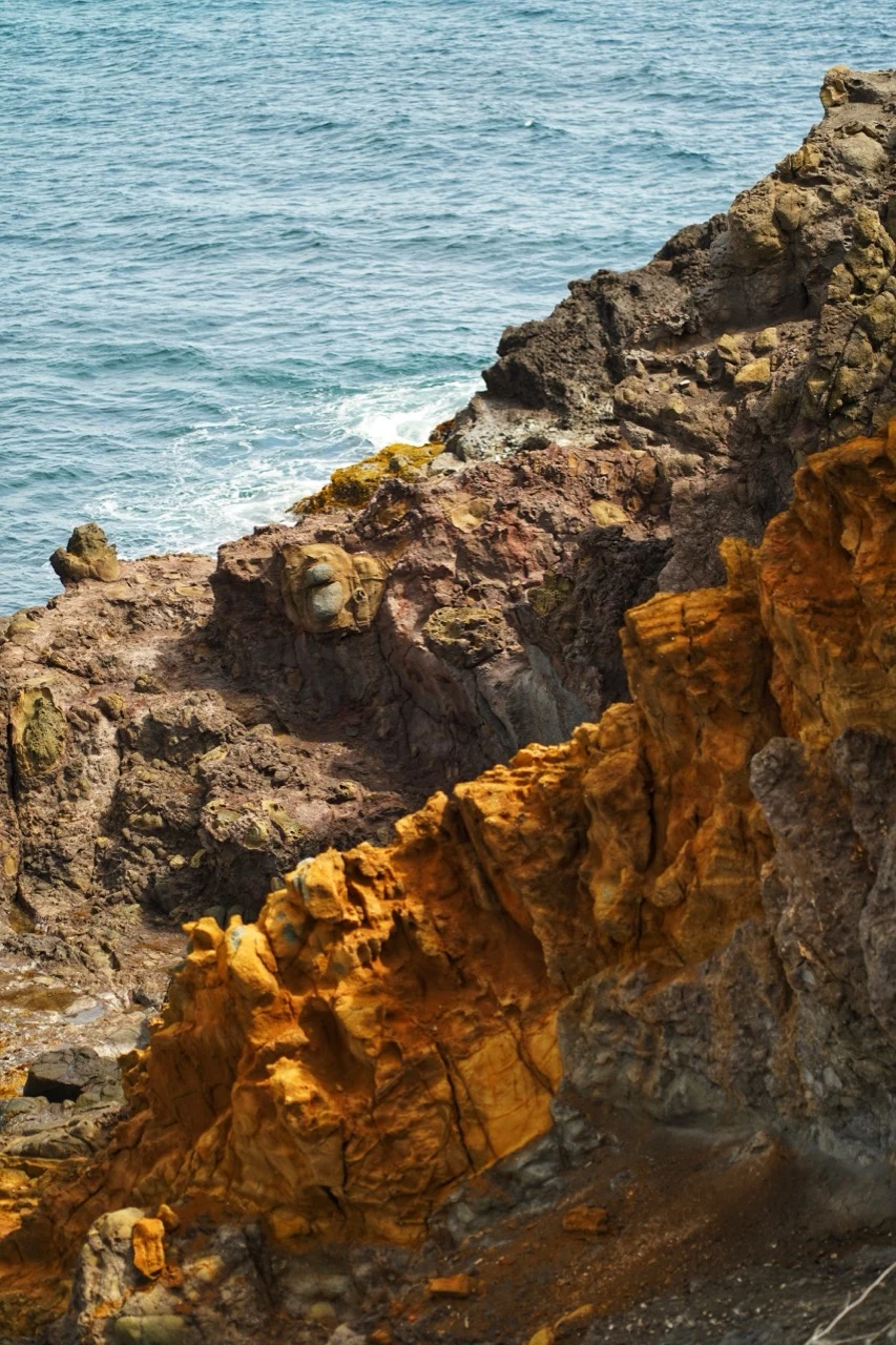 Roches volcaniques aux couleurs ocre et brune au bord de la mer